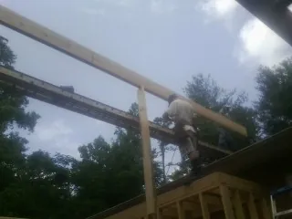 Carpenter setting a ridge beam over a new addition frame — Ice Dam Removal by Roofing Brothers in Osterburg