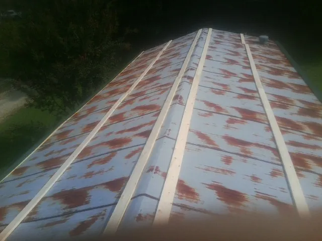 Rusted metal roof panels with new wood purlins before replacement — Storm Damage Roof Repair in Osterburg by Roofing Brothers