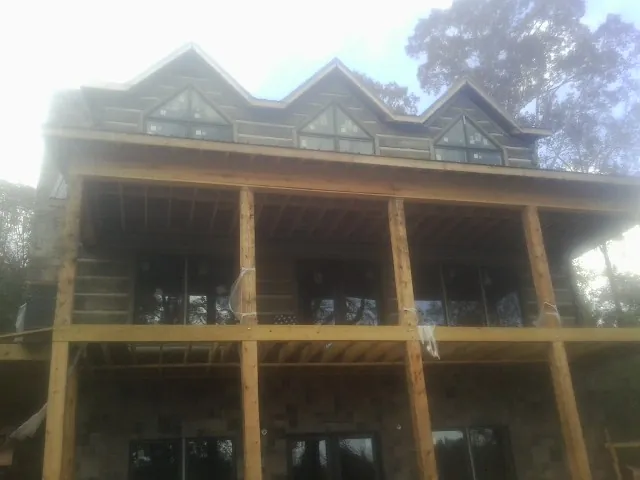 Dormers and porch framing on a large log home under construction — Roof Coating work by our crew in Osterburg