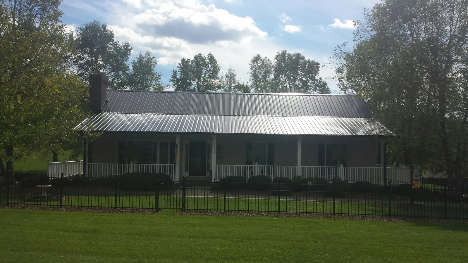 Gray metal roof on a brick ranch with a full width front porch — Gutter Guard Installation work by our crew in Osterburg