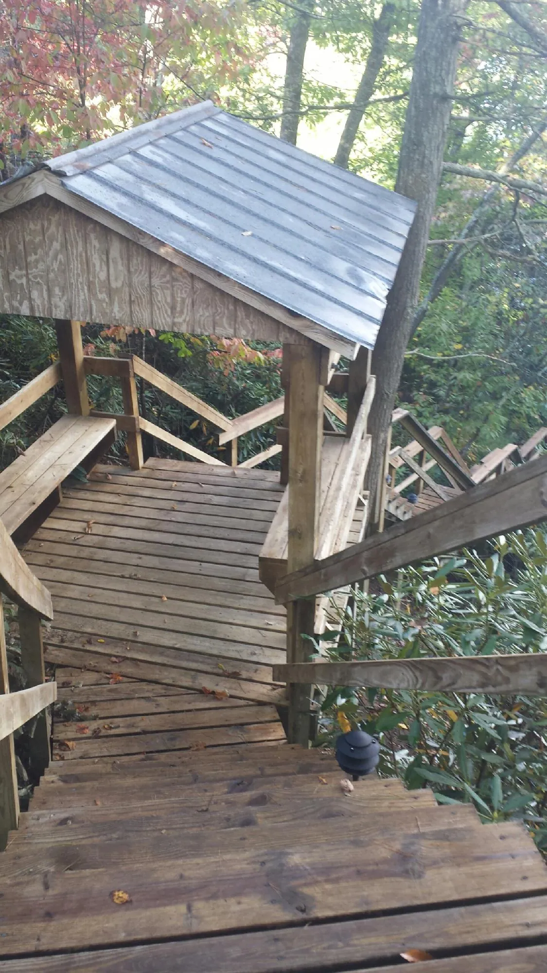 Metal roofed shelter over wooden steps on a wooded walkway — Skylight Repair & Installation work by our crew in Osterburg