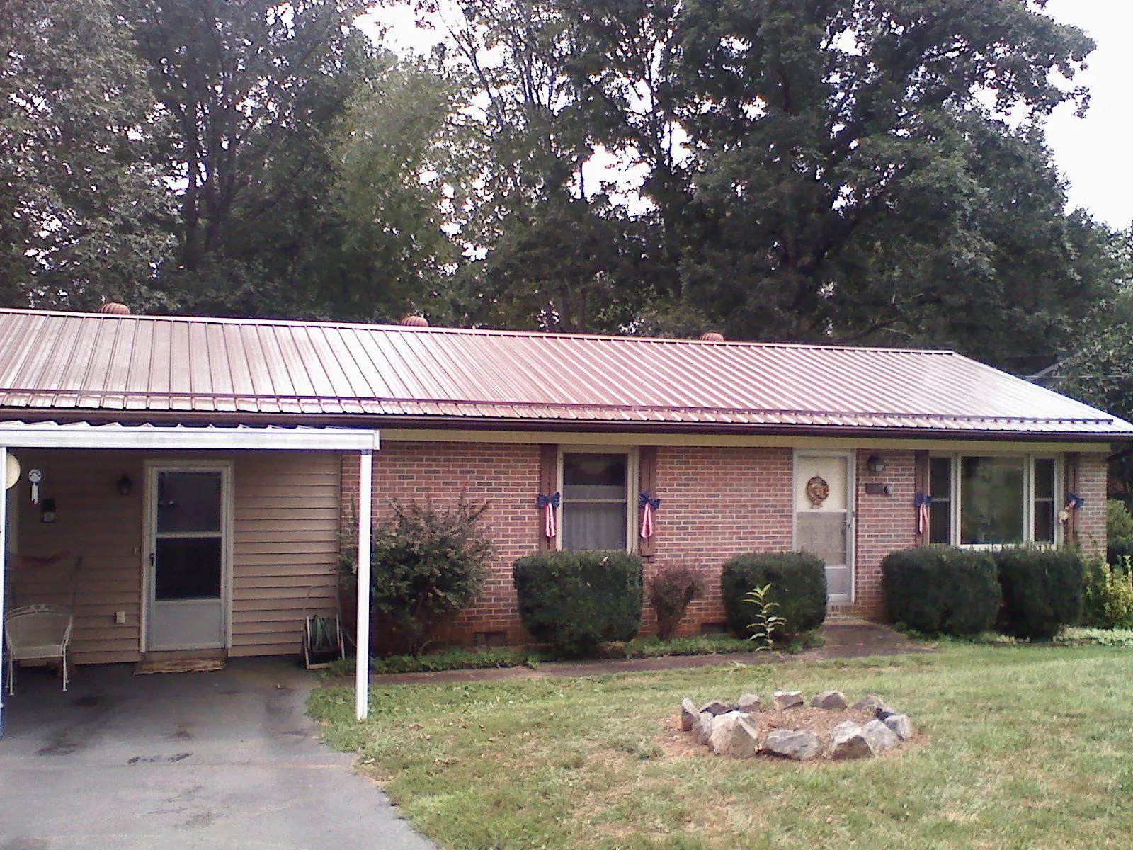 Bronze metal roof and carport on a brick ranch home — Roof Repair work by our crew in Osterburg