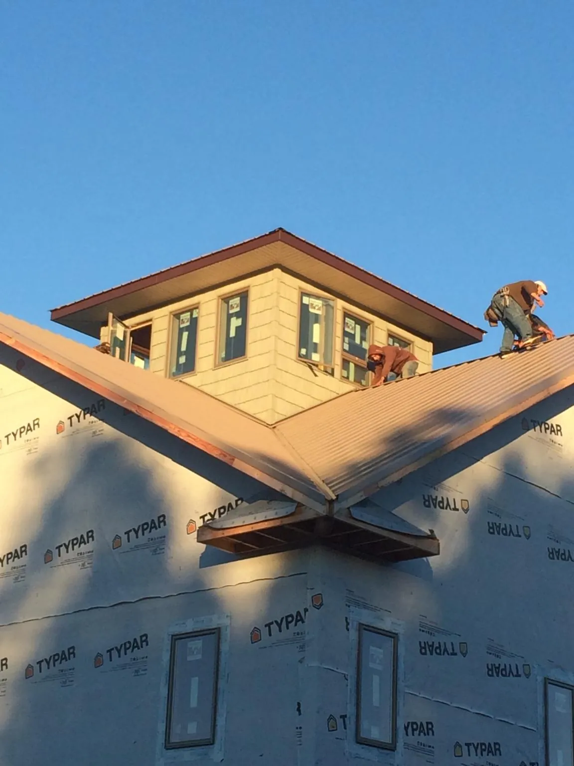 Roofers working around a rooftop cupola on a new metal roof at sunset — Roof Waterproofing in Osterburg by Roofing Brothers
